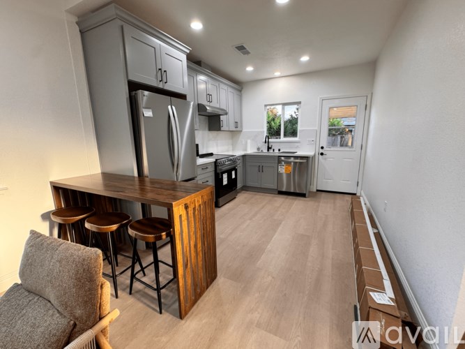 A kitchen with a refrigerator, stove, and bar stools.