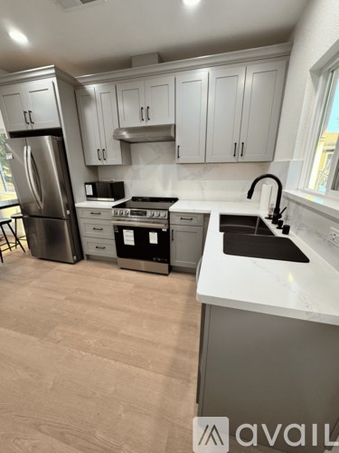 A kitchen with white cabinets and a stainless steel refrigerator.