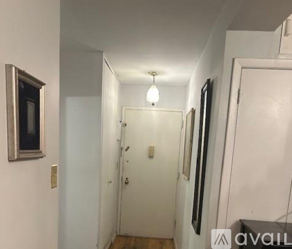A hallway with a white door and a light on the ceiling.