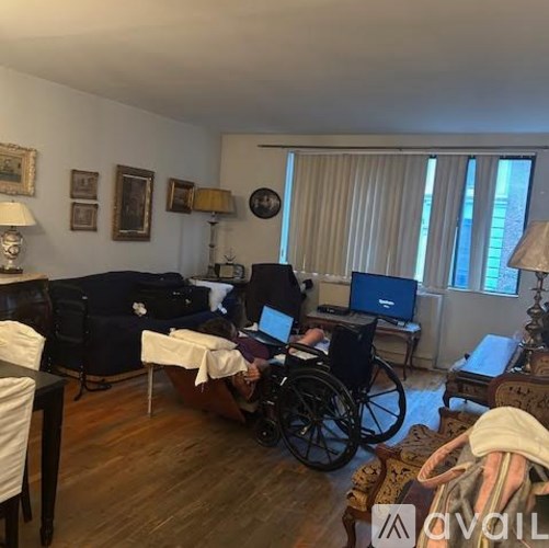 A man in a wheelchair is working on a laptop in a living room.