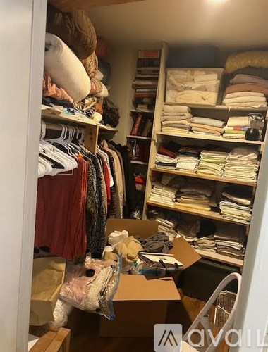 A room with a closet full of clothes and a box on the floor.