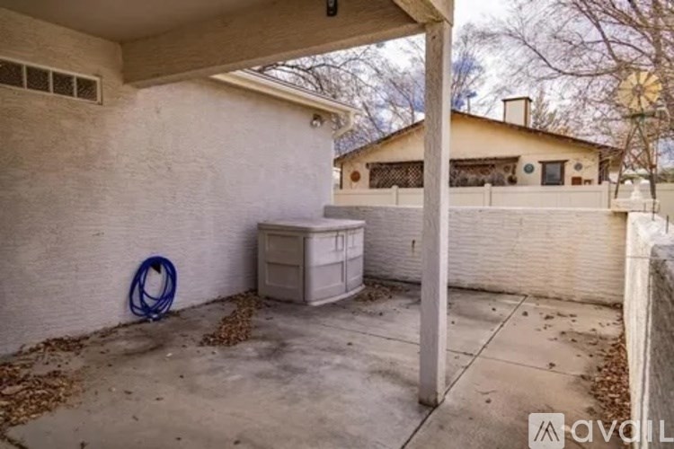 A backyard with a white fence and a blue hula hoop on the ground.