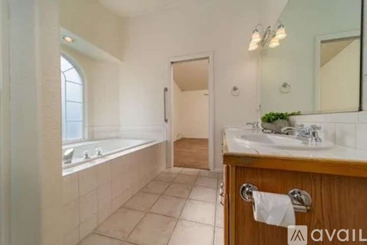 A bathroom with a tub, sink, and mirror.