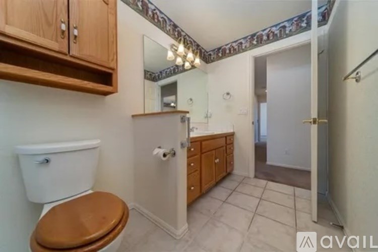 A bathroom with a toilet, sink, and wooden cabinets.