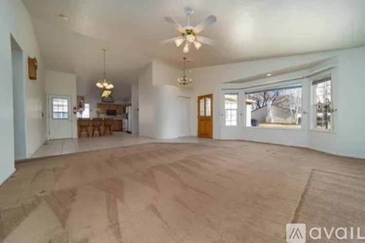 A spacious living room with a ceiling fan and hardwood flooring.
