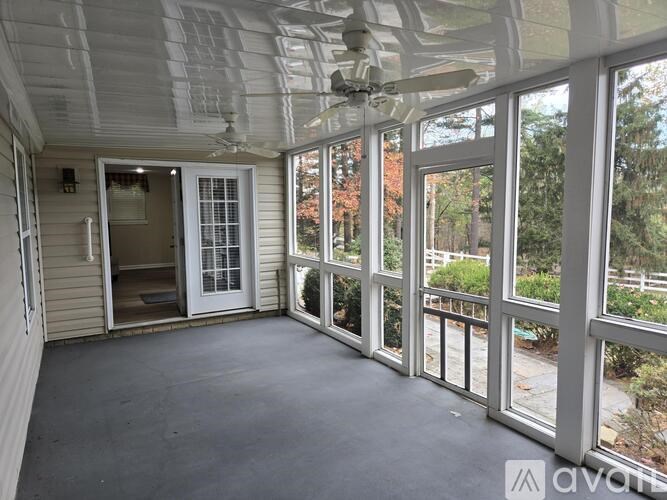 A screened porch with a ceiling fan and sliding glass doors.