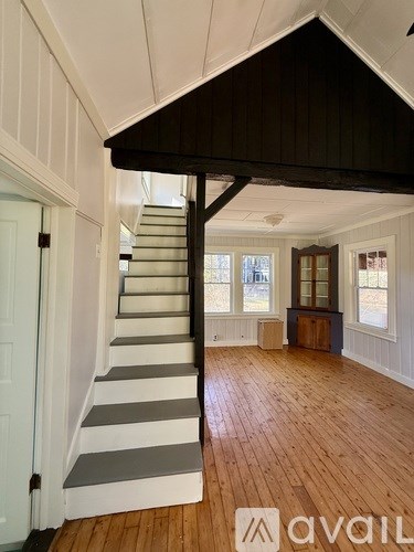 A wooden staircase with white risers and a black handrail.