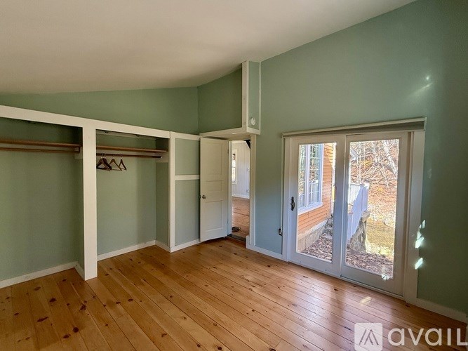 A room with wooden floors and a sliding glass door leading outside.