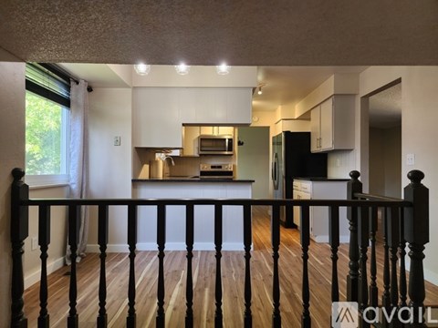 A kitchen with white cabinets and a black fridge is seen from the balcony.