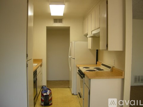 A small kitchen with white appliances and a wooden counter.
