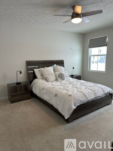 A bedroom with a large bed and a ceiling fan.