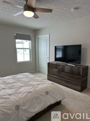 A bedroom with a bed, dresser, and television.