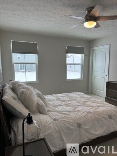 A bedroom with a bed, a ceiling fan, and a window with blinds.
