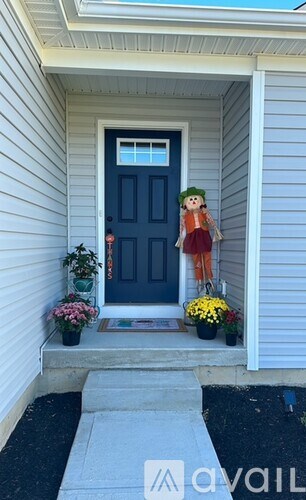 A doll is standing on the porch of a house.
