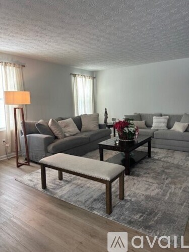 A living room with a grey couch, a coffee table, and a lamp.