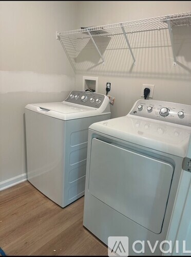 A white dryer is next to a white washer in a small laundry room.