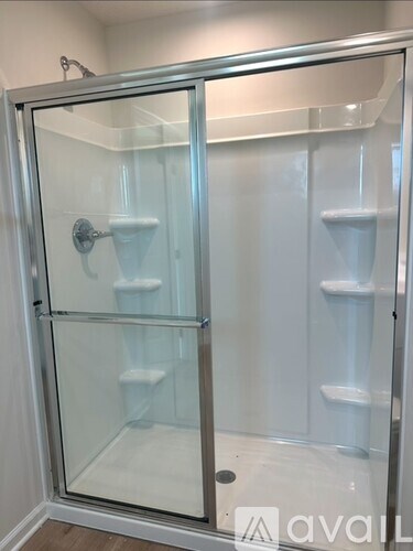 A glass shower door with a silver frame and a silver handle.