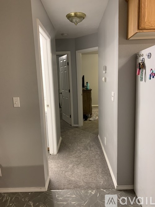 A hallway with a refrigerator on the right side.