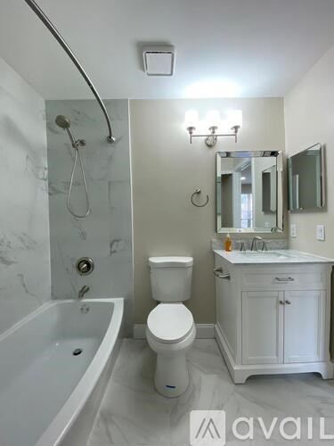 A white bathroom with a tub, toilet and sink.