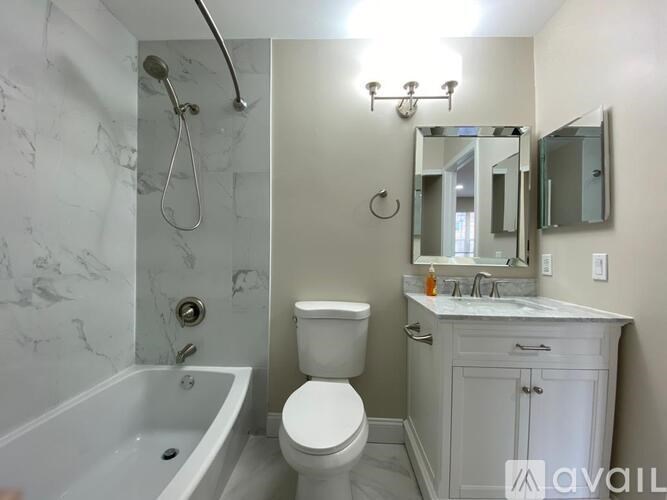A bathroom with a white toilet, a bathtub, and a sink.