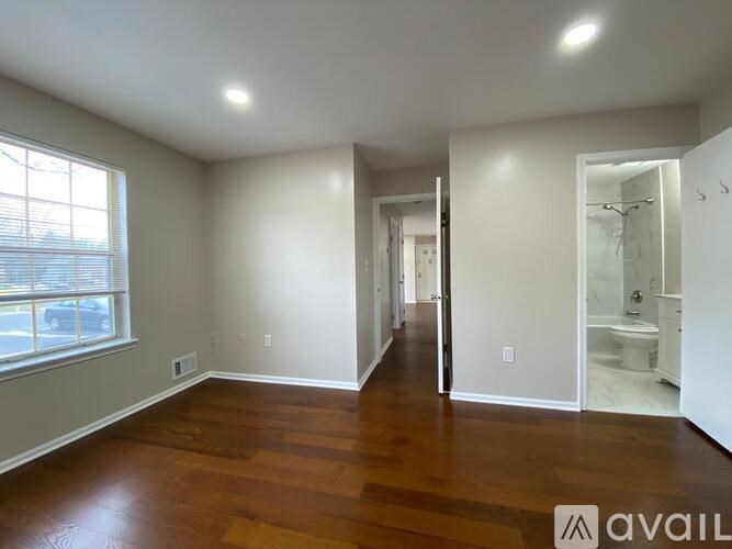 A spacious room with wooden floors and white walls.