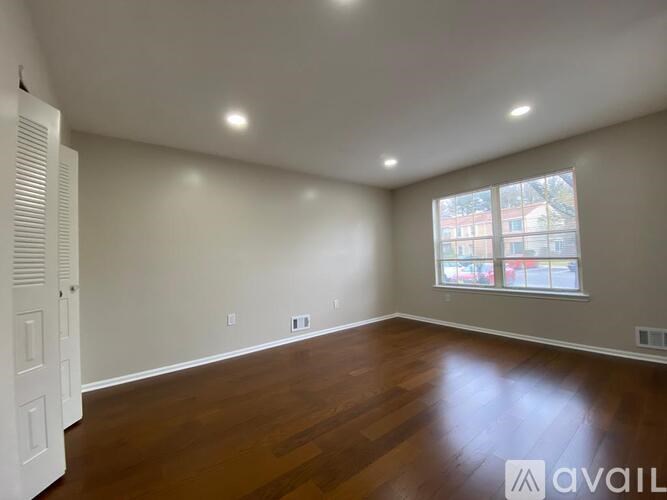 A room with wooden floors and a window showing a view of a building outside.