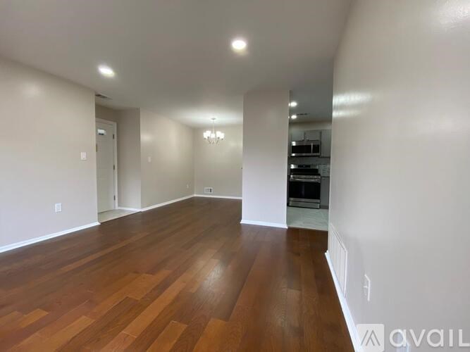 A spacious room with wooden flooring and white walls.