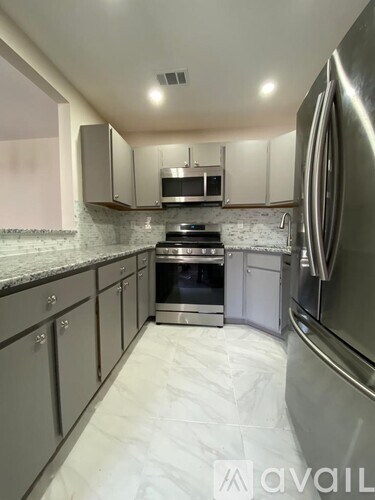 A kitchen with a stainless steel refrigerator and a marble countertop.