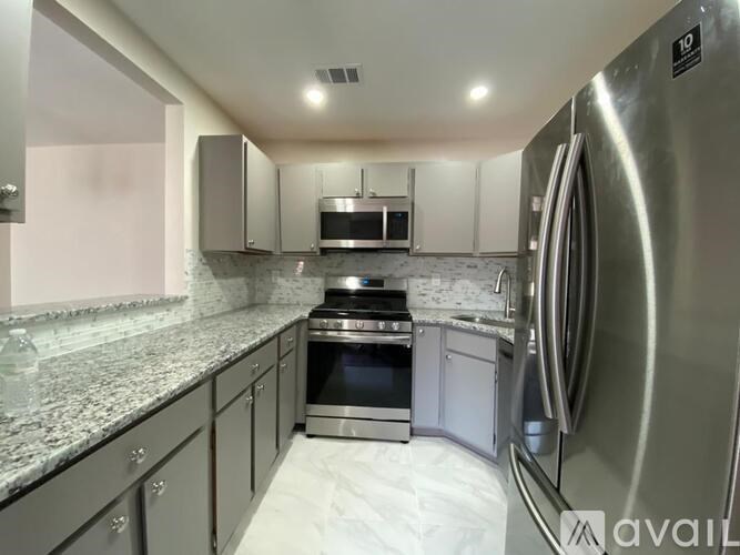 A modern kitchen with a stainless steel refrigerator and a granite countertop.