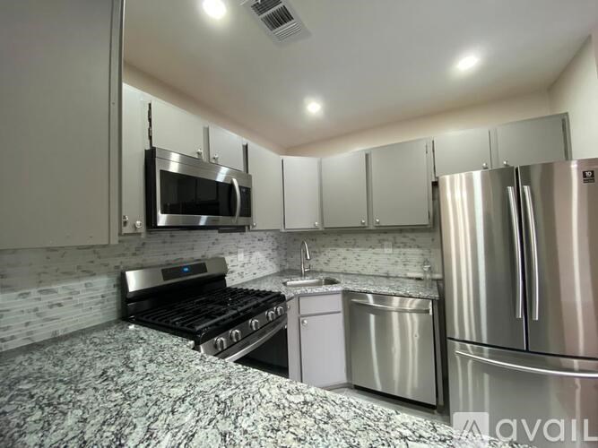 A modern kitchen with stainless steel appliances and a marble countertop.