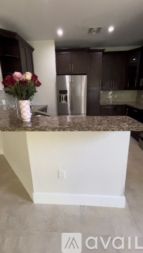 A kitchen with a granite countertop and a vase of flowers.