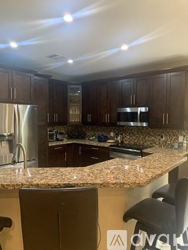 A kitchen with granite countertops and dark wood cabinets.