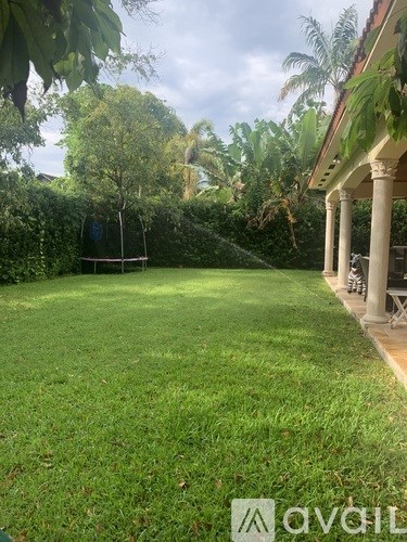 A backyard with a swing set and a house with columns.