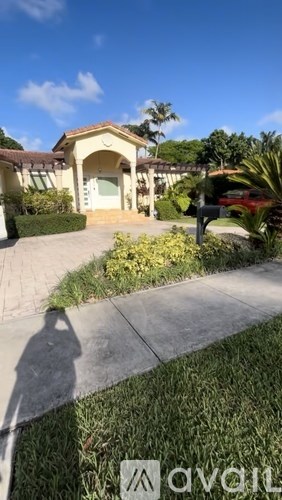 A house with a driveway and a shadow of a person on the ground.