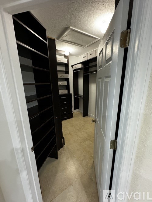 A hallway with a white door and a black shelf.