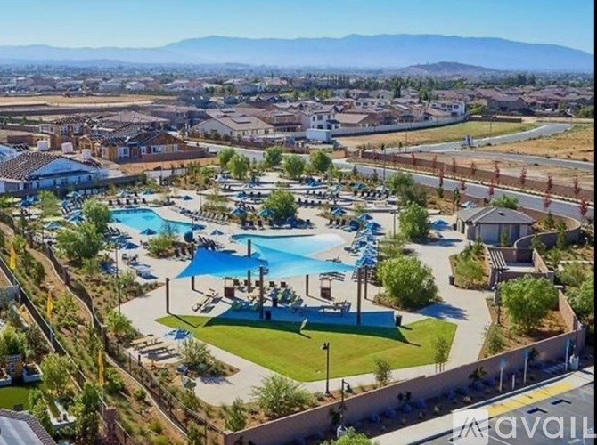 A large outdoor pool area with a slide and a hot tub surrounded by a fence.
