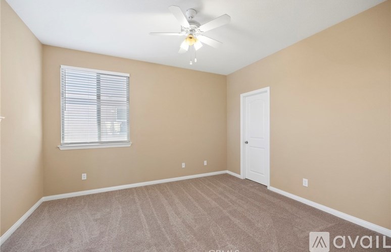 A room with a ceiling fan and a window with blinds.