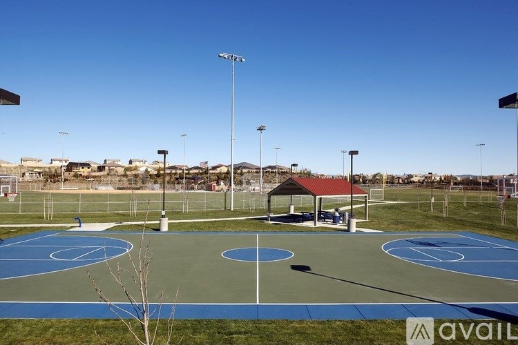 A basketball court with a blue and green surface and a red roofed structure in the middle.