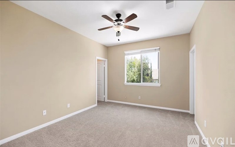 A room with a ceiling fan and a window.