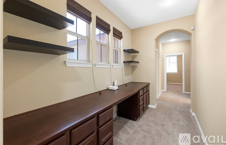 A room with a long brown table and shelves above it.