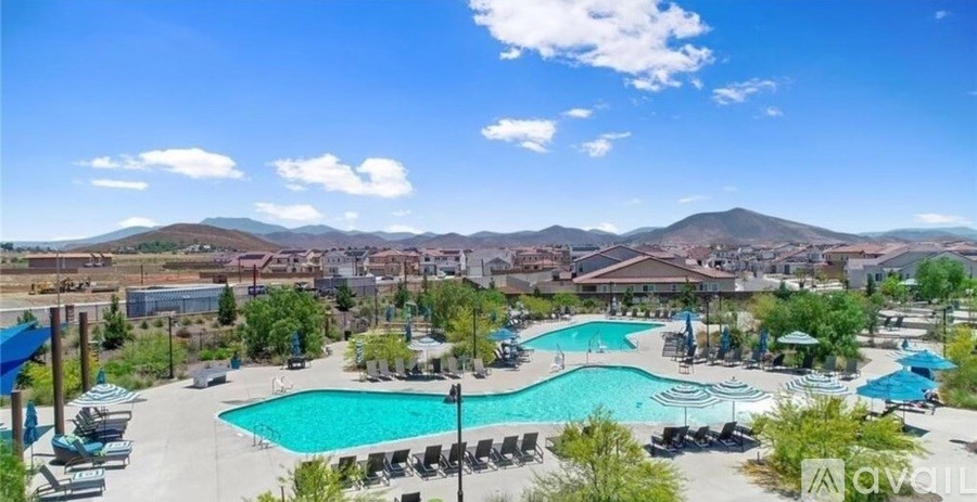 A large outdoor swimming pool surrounded by lounge chairs and umbrellas.