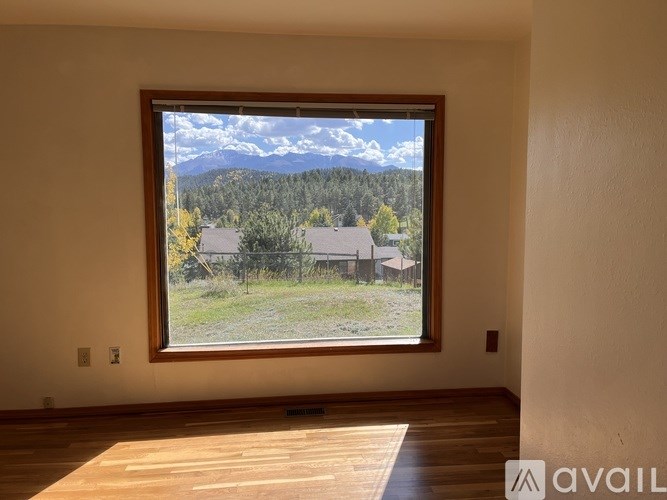 A room with a large window overlooking a mountain landscape.