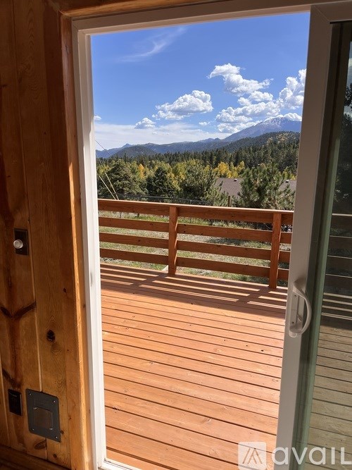 A wooden deck with a glass door leading to a mountain view.