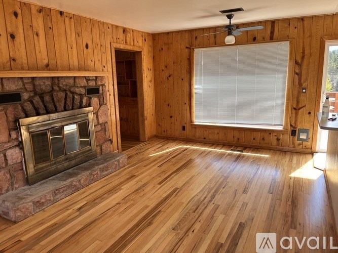 A room with wooden floors and a stone fireplace.