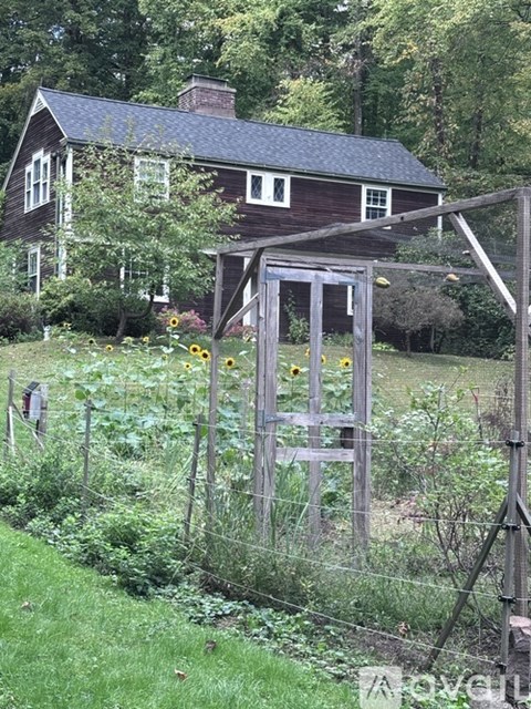 A wooden fence with a gate stands in a lush green garden.