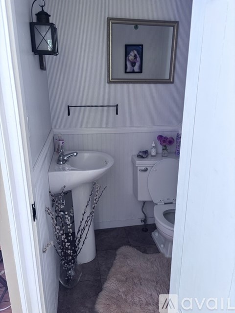 A small bathroom with a toilet, sink, and a mirror.