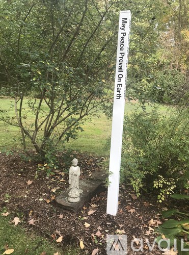A garden with a statue and a sign that says May Peace Prevail On Earth.