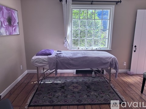 A bedroom with a bed, a rug, and a painting on the wall.