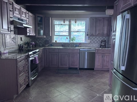 A kitchen with dark wood cabinets and a stainless steel refrigerator.