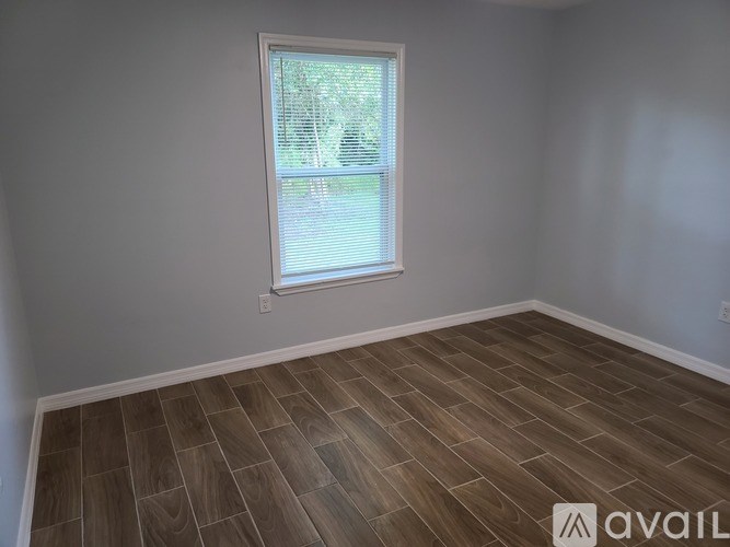 A room with a window and wooden flooring.